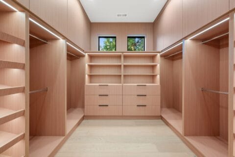 Large walk-in closet featuring a pinkish-beige wood interior with lots of space for hanging clothes.
