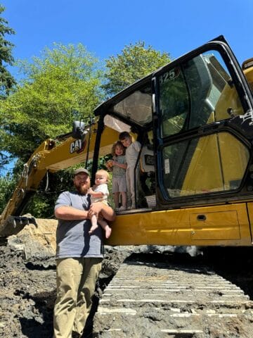 Operations manager Andrey standing on top of an excavator with his sons.