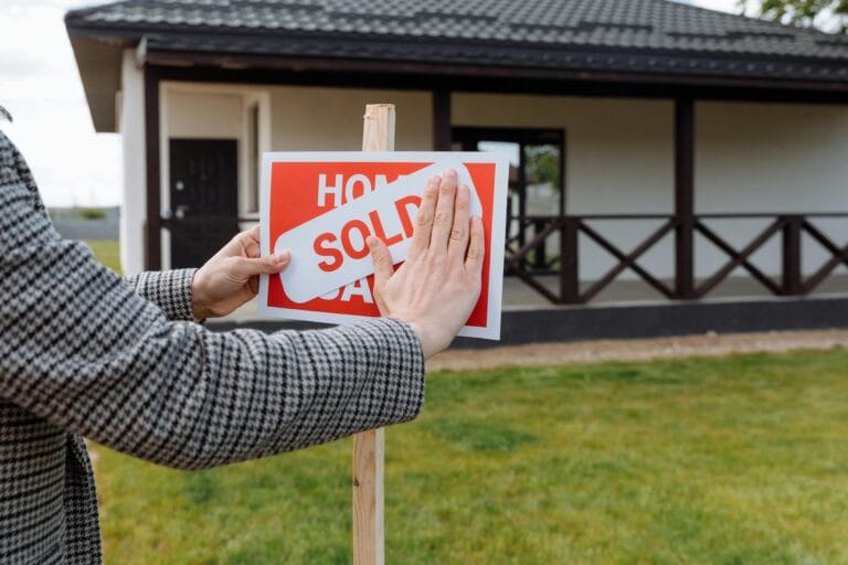 Realtor placing a SOLD sign over the top of a Home for Sale sign.