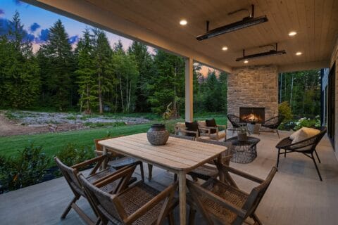 Outdoor dining scene with rustic tables and chairs overlooking a backdrop filled with forest trees.